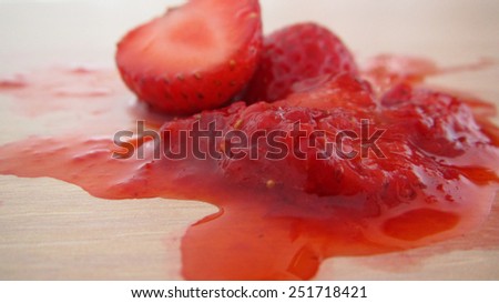 squashed strawberry in the puddle of red juice isolated over white background