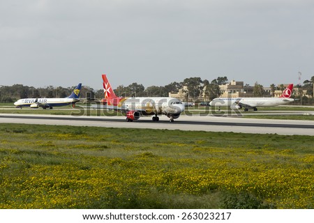 Luqa, Malta March 21, 2015: Air Malta Airbus A320-214 landing runway 13. A Ryanair 737-800 and Turkish Airlines A321 await their take off turn on taxiway \