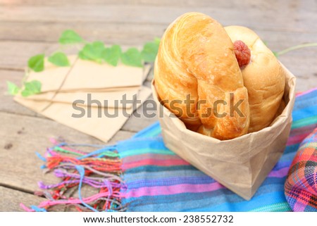 Breads in a paper bag on wooden table