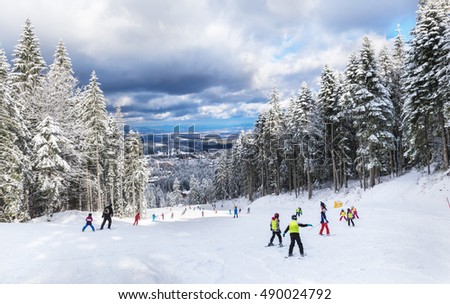 Group of young children learning to practice skiing on a ski slope in Poiana Brasov resort, in winter season, in Romania
