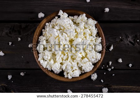 Cottage cheese in a bowl on wooden table. Style rustic. Selective focus.