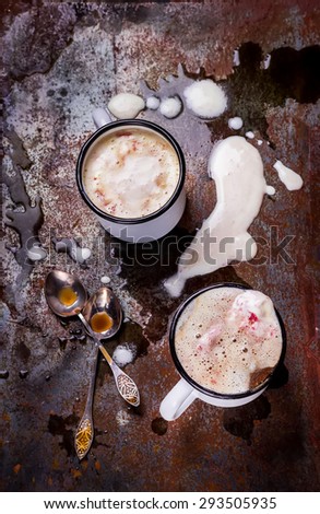 Two cups of coffee with ice cream and spoons on old metal background,