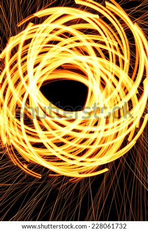 Arcs of fire, created by spinning steel wool that is set on fire.