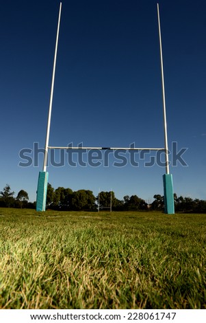 Football goal posts set against a blue sky with green grass in the foreground.
