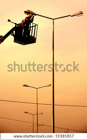 An electrical power utility worker in a bucket fixes the power line