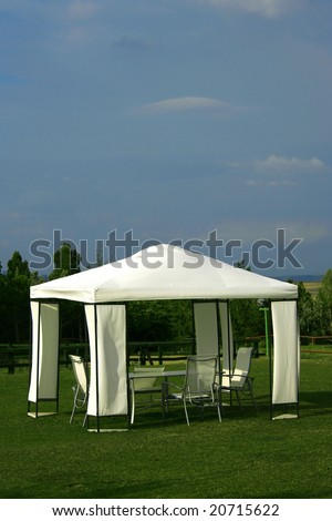 chairs and table under white picnic tent on green grass