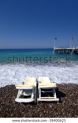 An image of lounge chairs at the beach with pebble stones