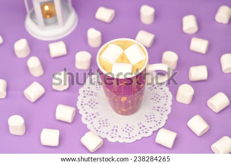Coffee with marshmallows in a purple mug on a purple background. White Christmas lantern on the background