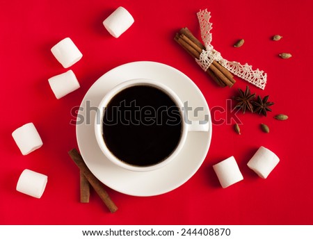 Coffee with spices and marshmallow on red textile background. Coffee beans, cinnamon sticks, cardamom and anise stars on the background. Valentine\'s Day. Top view