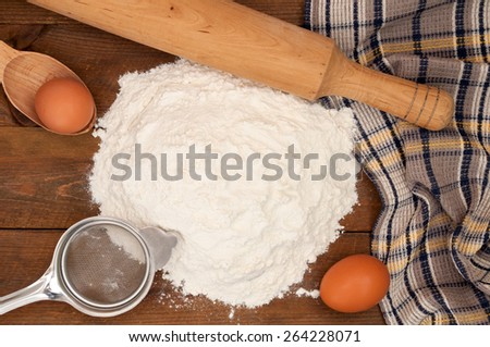 Dough preparation. Baking ingredients: eggs and flour, sieve and rolling pin on wooden background. Top view