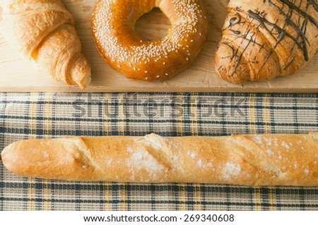 Fresh baking and croissants, french baguette for morning breakfast on wooden table with copy space. Top view. The image is tinted