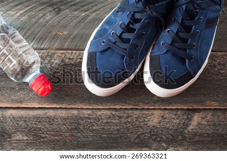Sport shoes and water on wooden background . Sport equipment top view