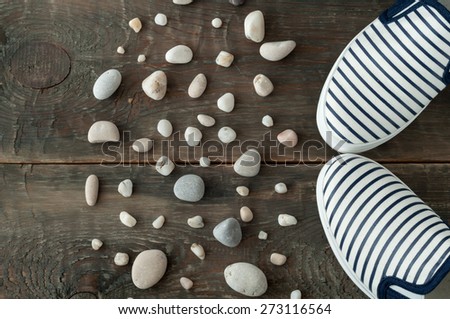 Shoes and stones on old wooden background. Top view sea shoes