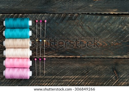 Sewing accessories. Spools of thread and pins on old wooden background. Top view