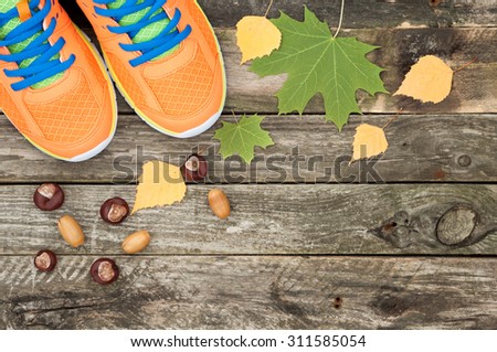 Sport shoes, autumn and chestnuts leaves on white wooden background. Top view sport equipment. Autumn sports outdoors. Top view