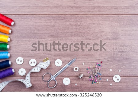 Sewing accessories. Spools of thread with different colors of rainbow, scissors, buttons, measuring tape and accessories for needlework on wooden background. Set for handmade top view