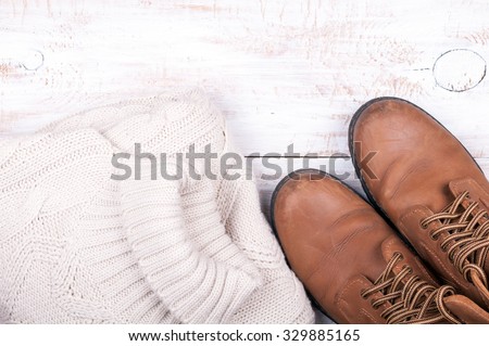 Men's autumn and winter casual clothes wool sweater and shoes on old white wooden background. Top view