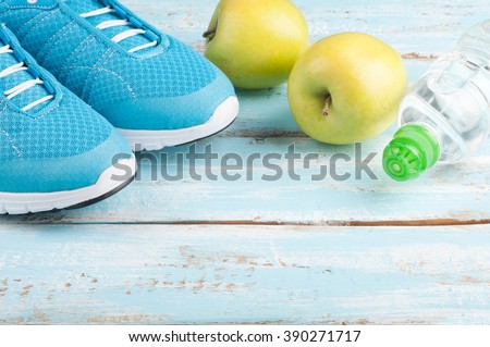 Sport shoes, apples, bottle of water on blue wooden background. Concept healthy lifestyle, healthy food, sport and diet. Sport equipment. Selective focus