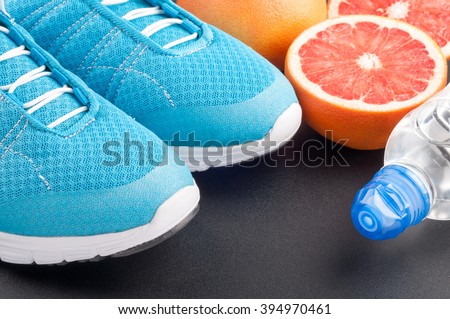 Blue sport shoes sneakers, citrus fruits, bottle of water on dark background. Sport equipment. Concept healthy lifestyle, healthy food, sport and diet. Selective focus