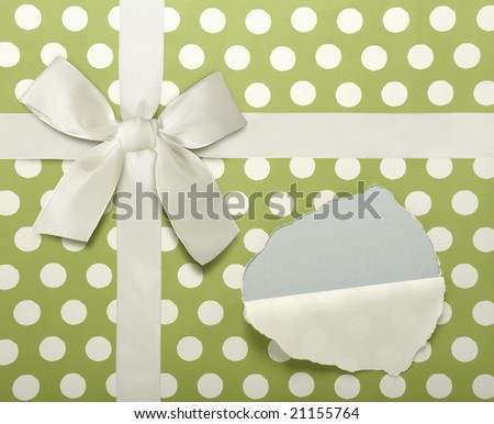 Green and white holiday wrapping paper with white bow. Paper is ripped to reveal area for copy or your own gift.