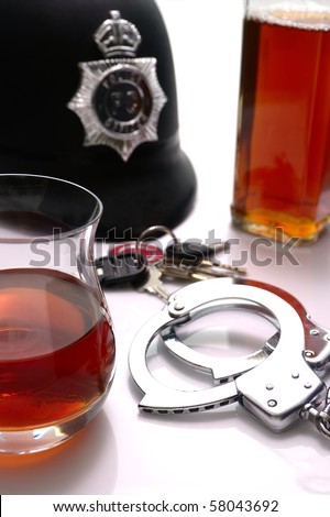 Conceptual \'driving under the influence of alcohol\' shot. High key scene of  handcuffs, british police hat, alcoholic drinks and car keys