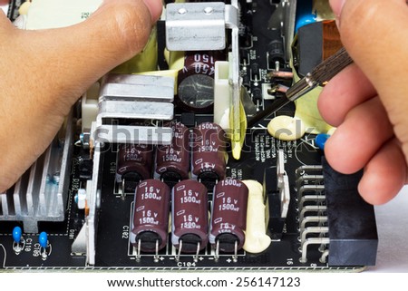 Electronic technician operates with circuit board.