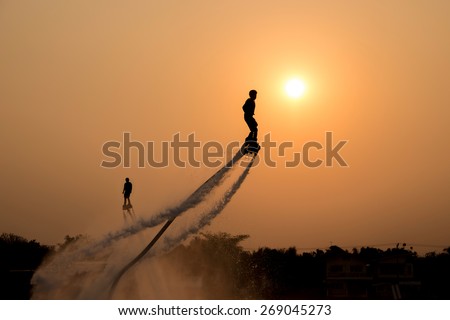 The new spectacular sport,Silhouette of two man showing the fly board in the river of Thailand