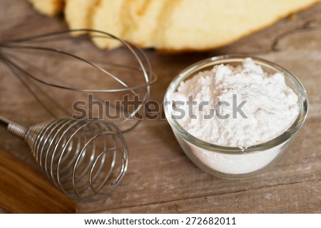 Bowl full of flour and baking tools for preparation on wooden background