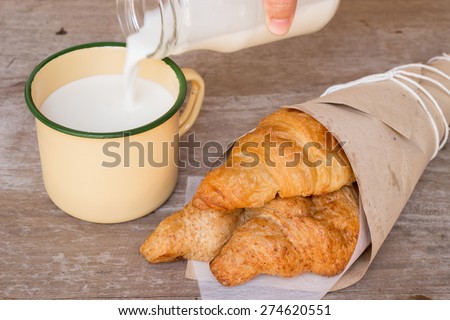 Fresh croissants in a paper wrap with milk from farm in a vintage glass