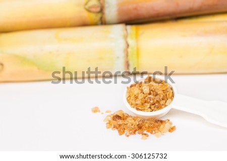 Brown sugar in 2/3 measuring spoon with sugar cane background