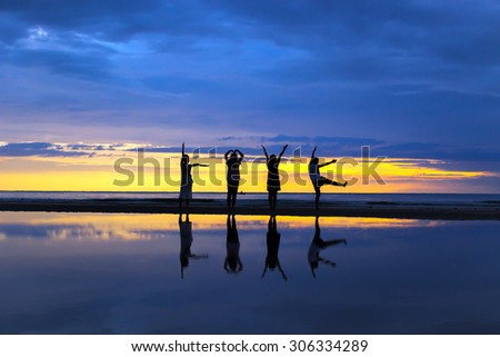 Silhouette of ladies show body language LOVE on the beach during a beautiful sunrise