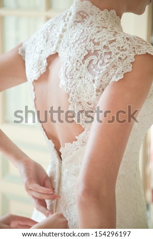 Bride putting on her white wedding dress