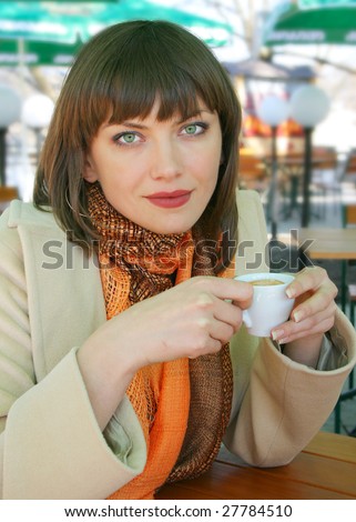 Young lady drinking coffee in a street cafe