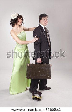 Happy young man is leaving his woman with small old suitcase