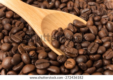 Coffee crop beans on bamboo spoon and wooden background