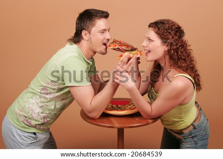 Young man and young woman feed pizza to each other