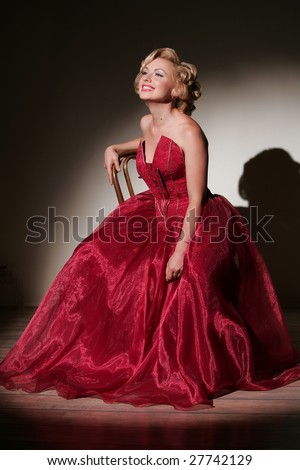stock photo Smiling pinup girl in red dress sit on the chair