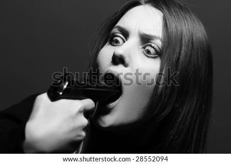 Beautiful young woman with gun in her open mouth