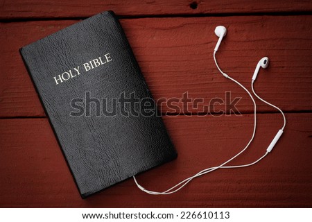 Contemporary image of a Bible with headphones.  Hearing the voice of God concept.