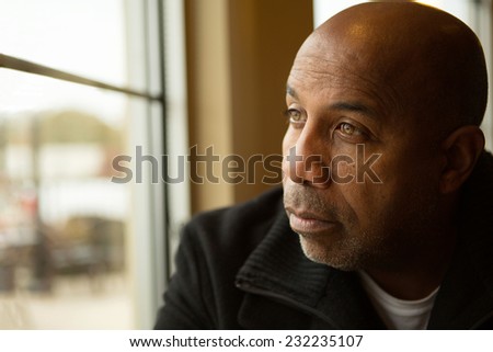 Sad African American man looking out the window.