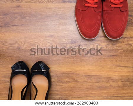 Pair of sneakers and pair of women\'s shoes on the wooden floor