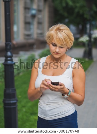 Young girl with the cellular phone in the hands writing sms