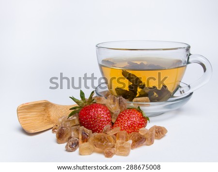 mug of hot green tea with strawberries and sugar