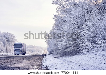light truck carries the load on a winter road along the forest
