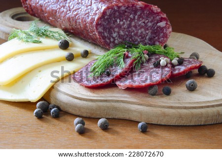 smoked sausage sliced Ã?Â¢??Ã?Â¢??cheese sliced Ã?Â¢??Ã?Â¢??dill spice pepper on a wooden board and a dark wooden background