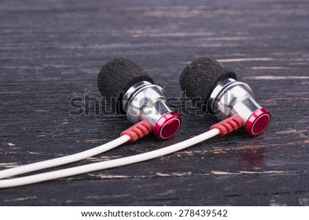 Headphones with white cord on wooden background close-up
