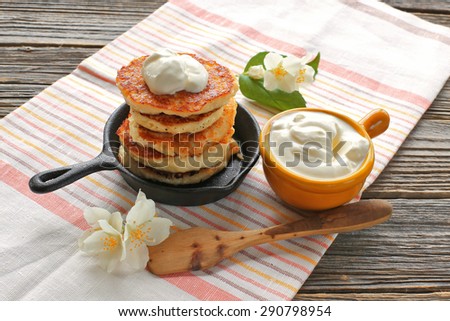 Cottage cheese pancake on cast iron frying pan with sour cream