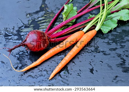 Raw beet and carrots on black background