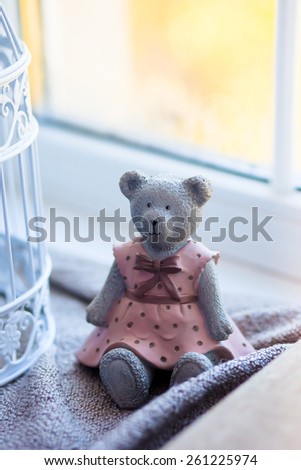 Indoor wooden toy bear sits on a windowsill
