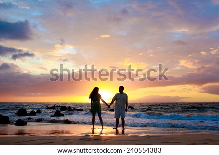 Silhouette couple holding hands on the beach at sunset